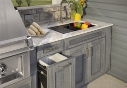 Open pullout storage cabinet beside the outdoor kitchen sink in the Jakab project by Mother Hubbard custom cabinetry.