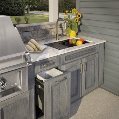 Open pullout storage cabinet beside the outdoor kitchen sink in the Jakab project by Mother Hubbard custom cabinetry.